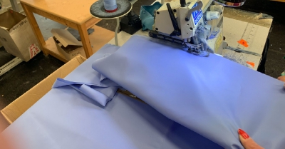 blue ppe material being sewn on a machine