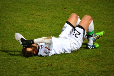 a footballer lies on his back on the pitch
