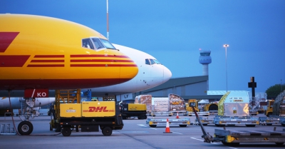 an airport with planes and DHL branded carts